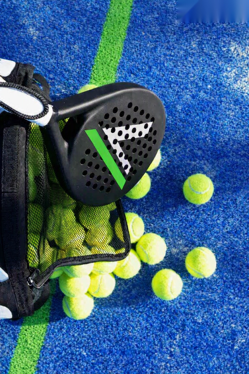 Pala de pádel y bolas sobre la pista azul con el logo de Valiria